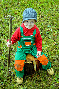 boy sitting on tree stump holding rake thumbnail