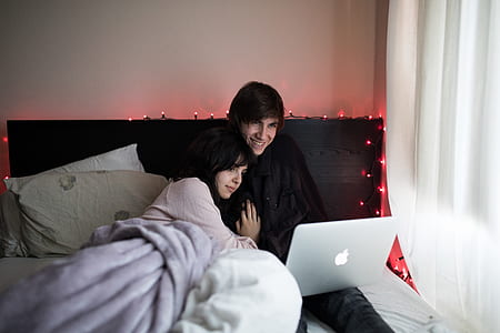 couple sitting on bed beside covered window thumbnail