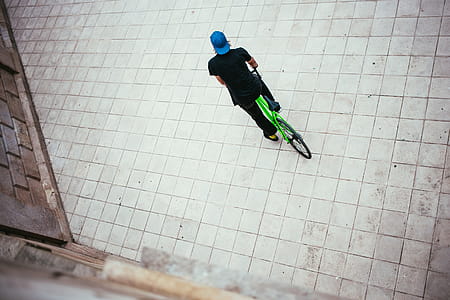 A young Caucasian male cyclist wearing blue cap halts on the street thumbnail