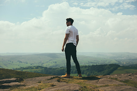 standing man in white T-shirt overlooking mountain thumbnail