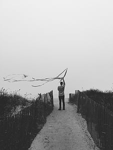 grayscale photography of man standing between fences thumbnail