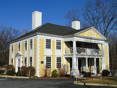 yellow and white painted house surrounded by bare trees at day time thumbnail