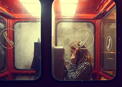 woman wearing striped long-sleeved shirt talking on the payphone thumbnail