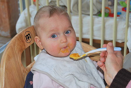 person feeding the baby while sitting on chair thumbnail
