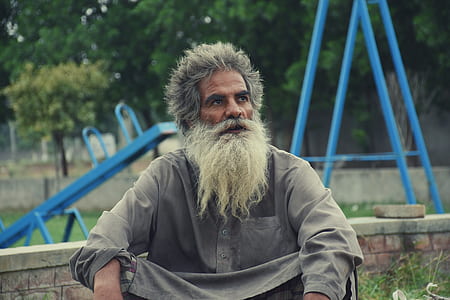 bearded man wearing thawb sitting on ground thumbnail