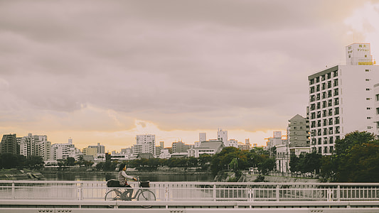 person riding gray bicycle on bridge during daytime thumbnail