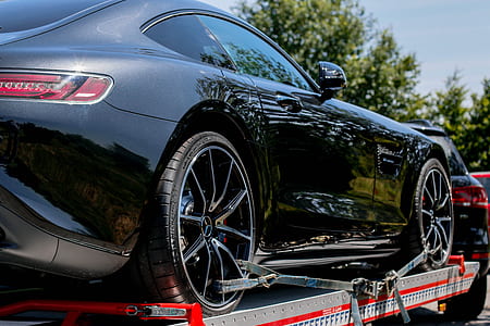 black Mercedes-Benz AMG GT on metal trailer attached to black SUV during daytime thumbnail