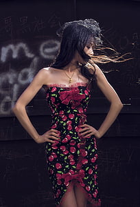 woman wearing red and black floral dress holding waists thumbnail