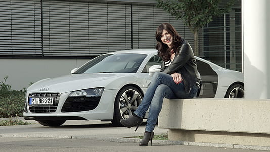 sitting woman in black leather jacket beside silver Audi sports coupe thumbnail