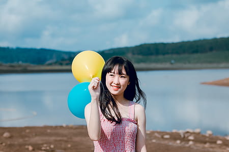 Woman in Pink Thick Strap Top Holding a Yellow and Blue Balloons thumbnail