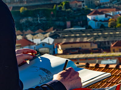 person holding pen while drawing during daytime thumbnail