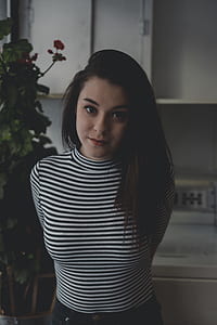 woman wearing black and white striped crew-neck shirt standing near green potted plants thumbnail