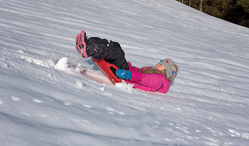 girl slide on snow during daytime thumbnail