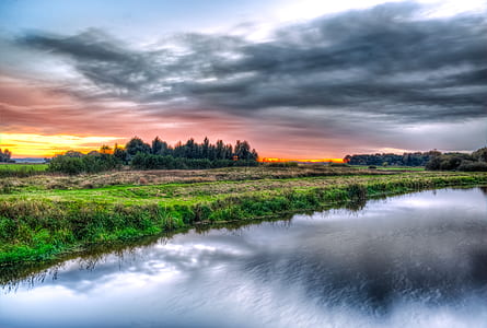 body of water near green grass during daytime thumbnail