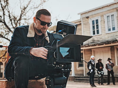 man sitting in front of black video camera thumbnail