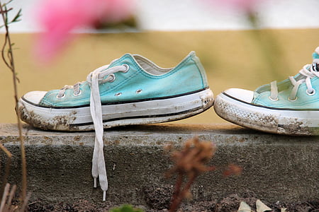 pair of teal-and-white low-top sneakers on gray pavement thumbnail