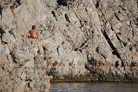 man sitting on gray rock formation thumbnail