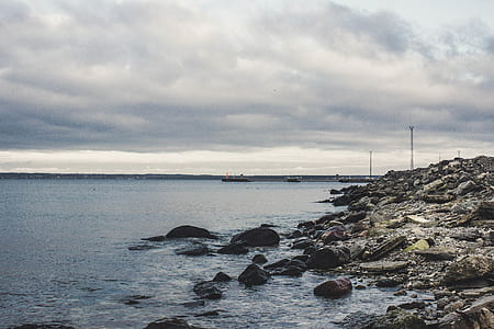 Rocks Beneath the Sea Under Cloudy Sky thumbnail