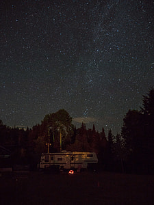 white RV trailer beside trees during starry nighttime thumbnail