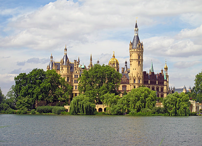 beige and maroon castle near forest and body of water thumbnail