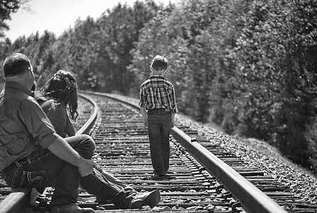 grayscale photo of three people on train railway thumbnail