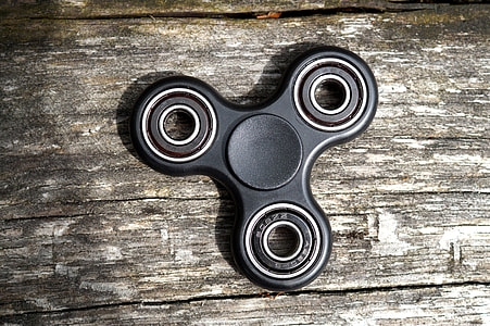 3-blade fidget spinner on gray wooden surface thumbnail