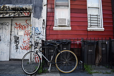 black and white beach cruiser bicycle parked near black metal fence thumbnail