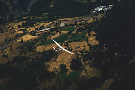 aerial photography of white airplane flying with mountain and trees view during daytime thumbnail
