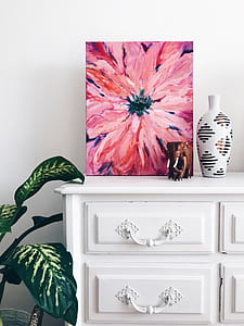 painting of pink petaled flower beside white vase on drawer chest thumbnail
