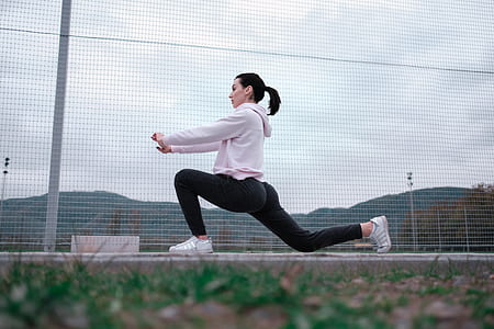 low angle photo of woman doing exercise near fence during daytime thumbnail