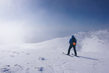 man wearing blue jacket standing on snow near mountain thumbnail