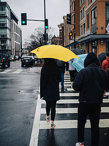 woman walking on pedestrian lane holding yellow umbrella thumbnail