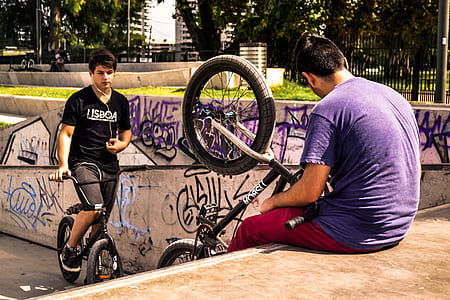 man riding on BMX bike beside graffiti wall thumbnail