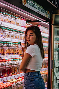 woman standing near beverage cooler holding orange juice bottle thumbnail