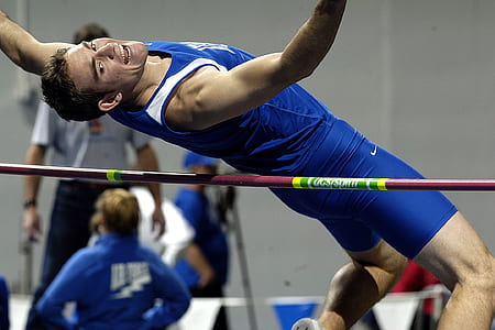 man jumping over red and green rod thumbnail