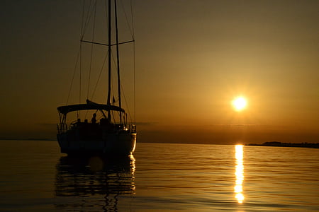 silhouette of boat on body of water at golden hour thumbnail