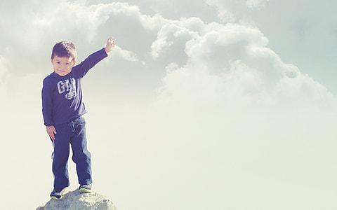 boy in black Gap sweatshirt and black bottoms standing on top of he cliff thumbnail