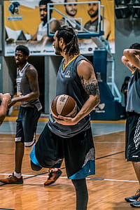 Man in Gray Sleeveless Shirt Carrying White and Brown Spalding Basketball thumbnail