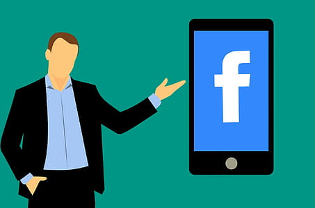 Man standing next to mobile device running facebook social media apps. thumbnail