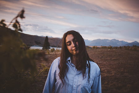 woman standing on grass field during cloudy day thumbnail