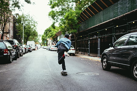 A young caucasian skateboarder wearing black cap skateboarding in the street thumbnail