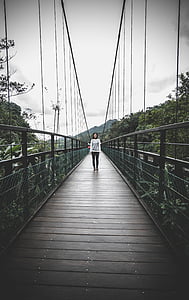person walking on brown wooden bridge thumbnail