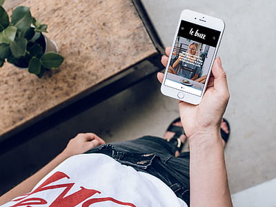 person holding iPhone showing woman sitting beside table thumbnail