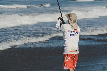 Person Holding Fishing Rod on Beach thumbnail