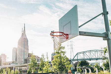photo of white and orange basketball hoop under cloudy sky thumbnail