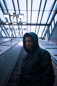 man wearing black zip-up hooded jacket on escalator thumbnail