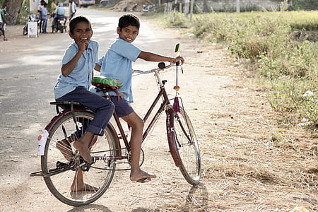 two boy wearing blue t-shirt riding on bicycle during daytime thumbnail