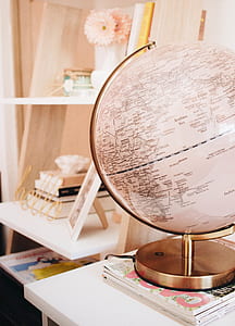 brass-colored framed desk globe near white wooden photo frame thumbnail