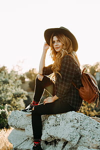 woman sitting on rock with brown leather backpack thumbnail