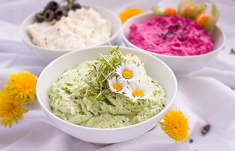 cream with daisy and green leaves on top inside white bowl thumbnail